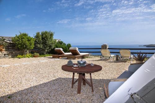 um pátio com uma mesa e cadeiras e o oceano em Aegean View - Seaside Apartment in Syros em Azolimnos