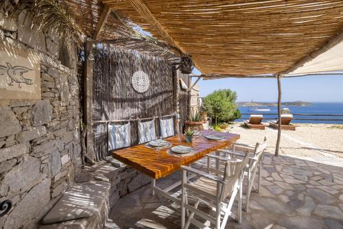 una mesa de madera y sillas en un patio con vistas al océano en Aegean View - Seaside Apartment in Syros en Azolimnos