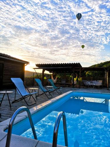 - une piscine avec des chaises longues et des cerfs-volants volant dans le ciel dans l'établissement Les nids de Bonnan, à Milhars