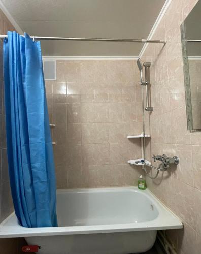 a bathroom with a tub with a blue shower curtain at Конгресс in Petropavlovsk