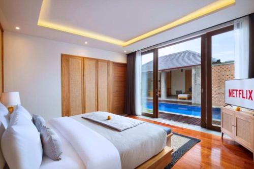 een slaapkamer met een groot bed en een televisie bij Kamalini 2 BR Private Pool Villa With Bathtub ZN68 in Canggu
