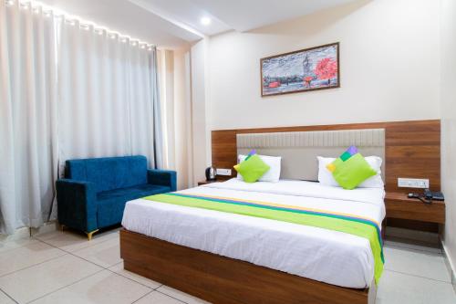 a hotel room with a bed and a blue chair at Treebo Royal Imperial, Bikaner Railway Station in Bikaner