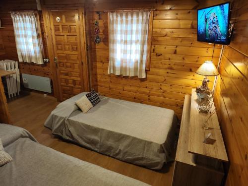Dormitorio con 2 camas y TV en una cabaña de madera en Cabaña los chorros, en Riópar