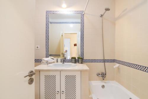 a bathroom with a sink and a tub and a mirror at Prainha Paradise - Algarve in Alvor
