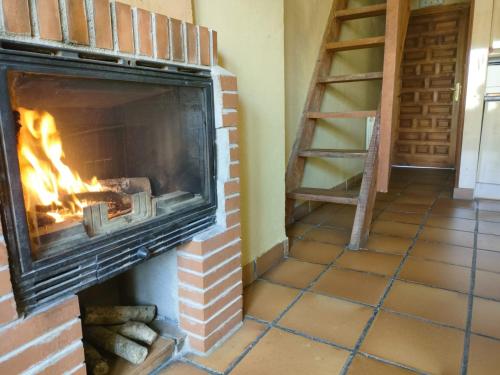 a brick fireplace with a fire in it at Alojamientos La Dehesa in El Berrueco