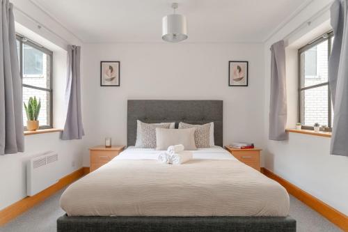 Schlafzimmer mit einem großen weißen Bett und Fenstern in der Unterkunft Holborn - 2BR Near Covent Garden -CityApartmentStay in London