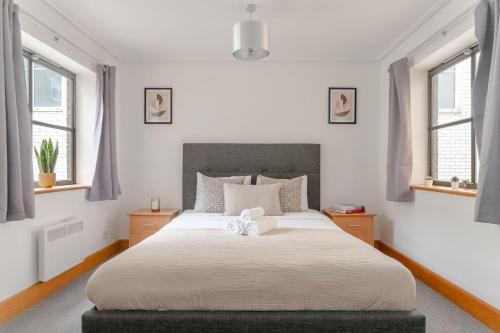 a bedroom with a large white bed with windows at Holborn - 2BR Near Covent Garden -CityApartmentStay in London