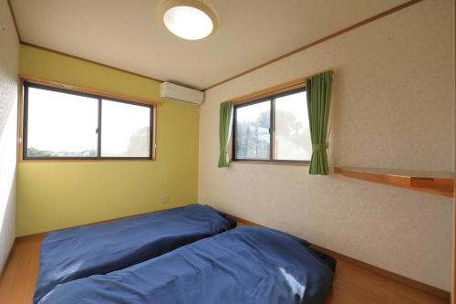 a bedroom with a blue bed and two windows at ペット同伴プランあり, 一棟貸し, 屋根付bbq, 薪サウナ, 広いお庭ドッグラン, 海まで車10分 in Miyamae
