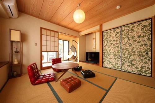 a living room with a table and red chairs at サウナ,ドッグラン付き施設 "ガーデンハウス九十九里" -Garden House KUJUKURI in Miyamae