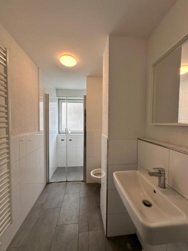 y baño blanco con lavabo y ducha. en BM01 bis BM04 Schöne Apartments in Frechen en Frechen