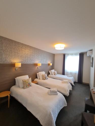 fila de camas en una habitación de hotel en Logis Hôtel Restaurant Clair Cottage, Chisseaux - Chenonceaux, en Chisseaux