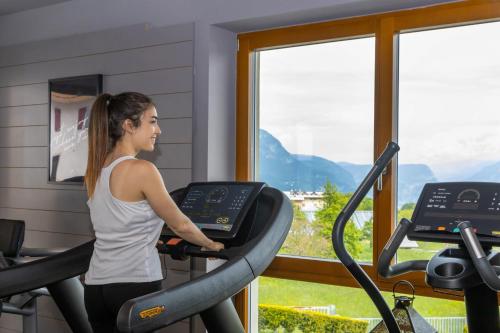 a woman running on a treadmill in a gym at SOLEA DOLOMITI Boutique Hotel in Fai della Paganella