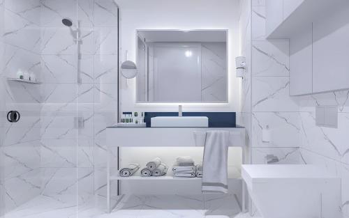 a white bathroom with a sink and a mirror at Orbi City Hotel Batumi Beach in Batumi