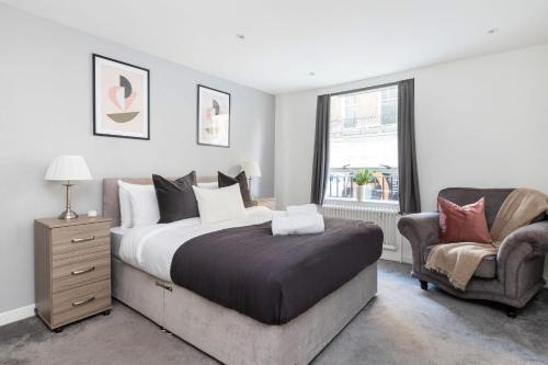 a bedroom with a large bed and a chair at Marylebone - Wimpole Street - CityApartmentStay in London