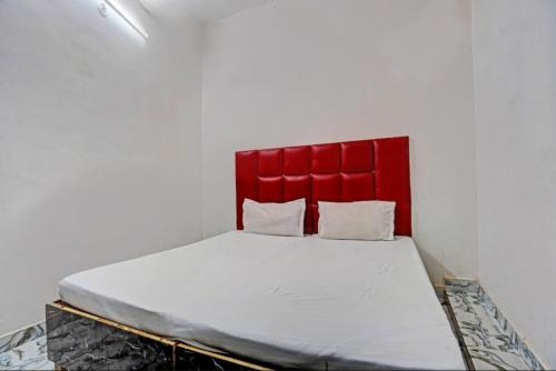 un lit avec tête de lit rouge dans une chambre dans l'établissement VR HOTEL, à Auraiya