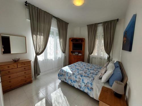 Schlafzimmer mit einem Bett, einer Kommode und Fenstern in der Unterkunft Casa Armilla in La Spezia