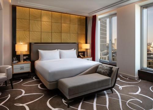 a bedroom with a bed and a chair and windows at Waldorf Astoria Berlin in Berlin