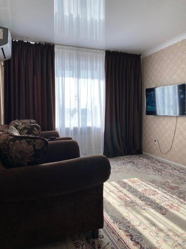 a living room with a couch and a flat screen tv at ИП.МЕДИНА in Taraz