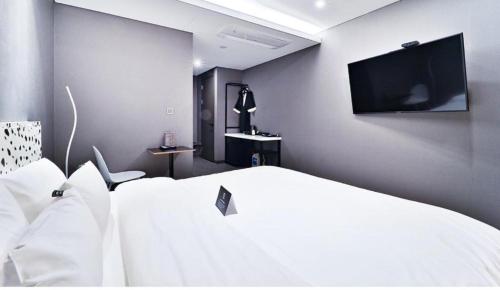 a bedroom with a white bed and a flat screen tv at Zam 101 in Busan