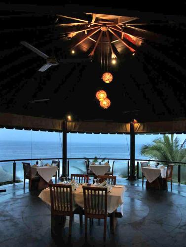 a restaurant with tables and chairs and a view of the ocean at Niraamaya Wellness Retreats, Surya Samudra, Kovalam in Kovalam