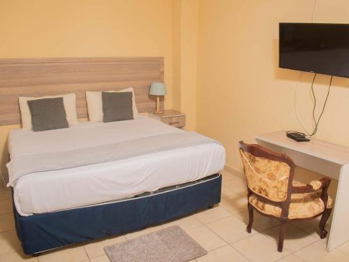 a bedroom with a bed with a desk and a television at River-Ridge Guest House in Gaborone