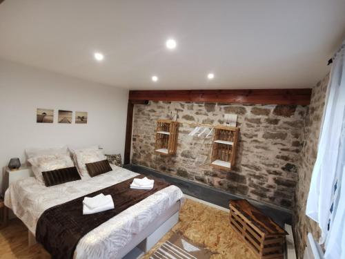 une chambre avec deux lits et un mur en pierre dans l'établissement Gîte Corrézien 3 pers. Piscine chauffée, à Chamboulive
