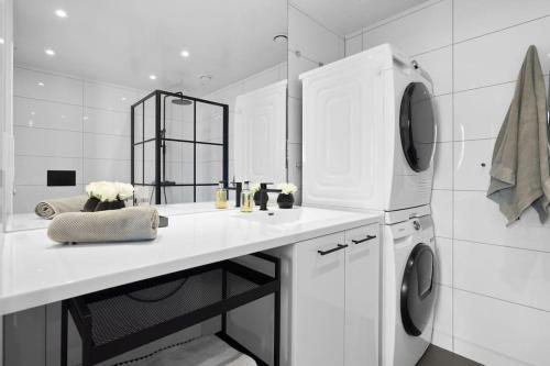 cocina blanca con fregadero y lavadora en Seafront Apartment at Sørengka OSLO, en Oslo