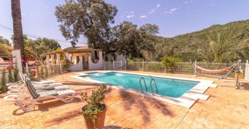 a swimming pool with lounge chairs and a hammock at Casa Rural Los Menestrales in Lora del Río