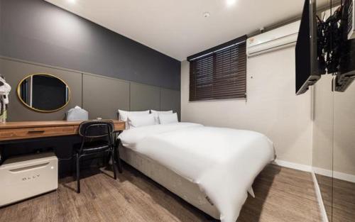 Brown Dot Hotel Suwon Jeongja Branch في سوون: غرفة نوم مع سرير أبيض كبير ومكتب