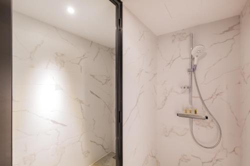 a shower in a bathroom with white marble walls at Beijing Pudi Hotel in Beijing