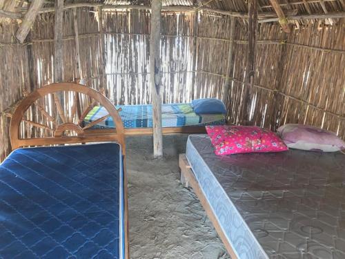 a room with two beds in a straw hut at Islas Bonitas in Arritupo Número Dos