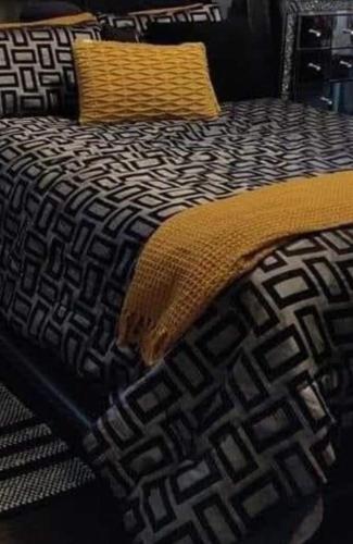 a bed with a black and white blanket on it at Double rooms available, near Safari Park & Hospital in Franche