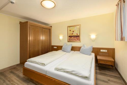 een slaapkamer met een groot bed met witte lakens bij IFA Breitach Apartments Kleinwalsertal in Mittelberg