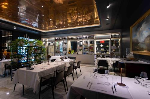 a restaurant with white tables and chairs and a kitchen at ibis Styles Milano Est Settala in Settala