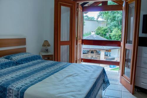 ein Schlafzimmer mit einem Bett und einem großen Fenster in der Unterkunft NOVO Maravilhosa casa de campo em Mairipora SP in Mairiporã