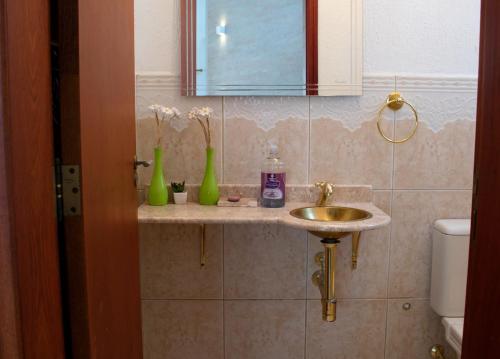 ein Badezimmer mit einem Waschbecken und zwei grünen Vasen in der Unterkunft NOVO Maravilhosa casa de campo em Mairipora SP in Mairiporã