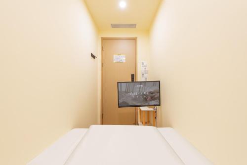 a small room with a bed and a tv at Lemon Hotel - Metro Line 1 Line 7 Changshu Road 200 meters in Shanghai