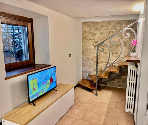 a living room with a tv and a staircase at Vittoria holiday house - Tulip Apartment in Stresa