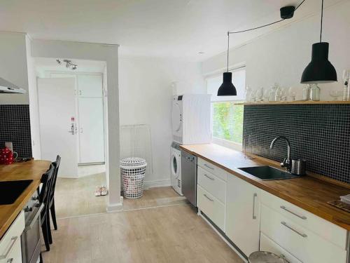 eine Küche mit weißen Schränken, einer Spüle und einem Geschirrspüler in der Unterkunft Lovely 1-bedroom condo in Aarhus C in Arhus