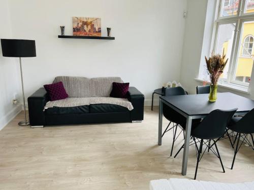 a living room with a black couch and a table at Lovely 1-bedroom condo in Aarhus C in Aarhus