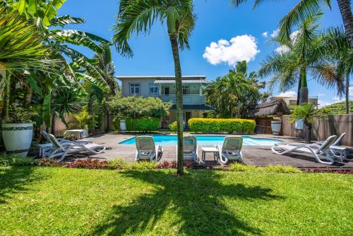ein Resort-Pool mit Liegestühlen und Palmen in der Unterkunft Kisana Residence - Studio with spacious balcony shared pool garden in Grand Baie