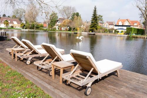 een rij ligstoelen op een steiger naast een meer bij Villa Privée avec Piscine et Lac in Saint-Gratien