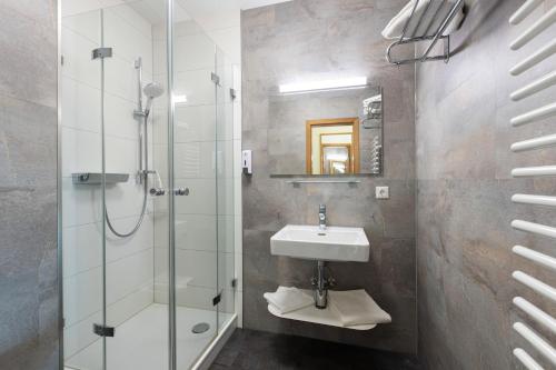 a bathroom with a glass shower and a sink at IFA Breitach Apartments Kleinwalsertal in Mittelberg