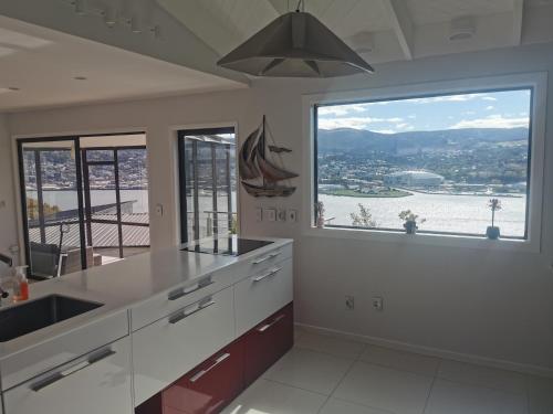 a kitchen with a large window with a boat on it at Luxury Harbour view in Dunedin