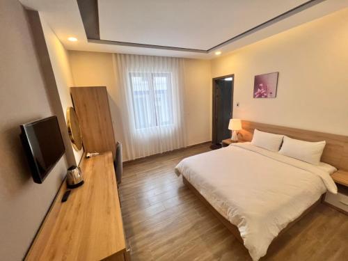 une chambre d'hôtel avec un lit et une télévision dans l'établissement Q's House Dalat, à Đà Lạt