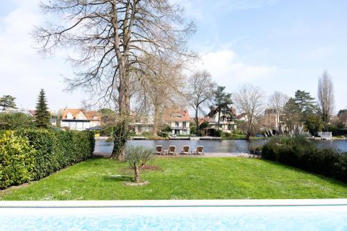 uitzicht op een tuin met stoelen en een meer bij Villa Privée avec Piscine et Lac in Saint-Gratien