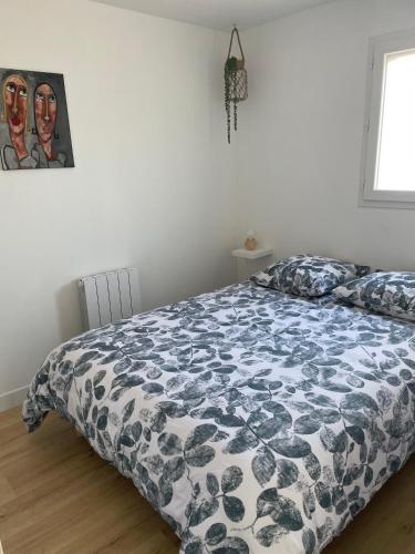 une chambre avec un lit avec une couette noire et blanche dans l'établissement Appartement proche mer, à Aytré