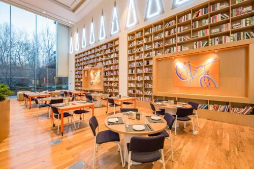 a restaurant with tables and chairs in a library at Beijing Pudi Hotel in Beijing