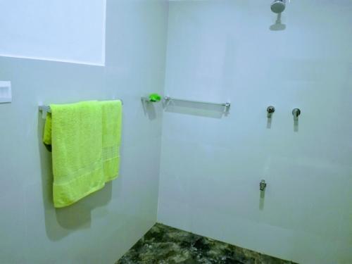 biała łazienka z zielonym ręcznikiem na ścianie w obiekcie Hideaway Homestay Habarana w mieście Habarana