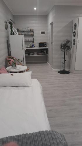 a bedroom with a white bed and a refrigerator at Biesiesvlei 1 in Plettenberg Bay